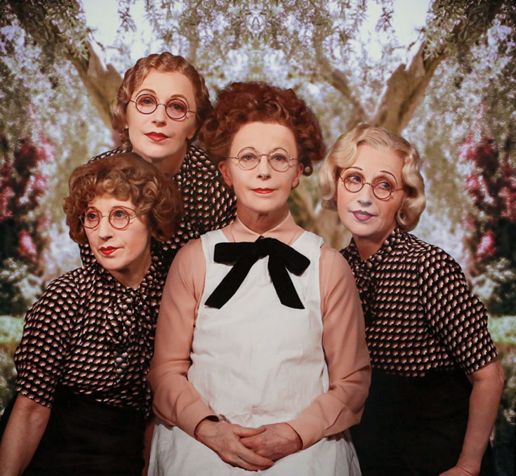 A group of four women, all wearing glasses. Three are wearing spotted shirts and the other is wearing a long sleeve shirt under a tank dress.